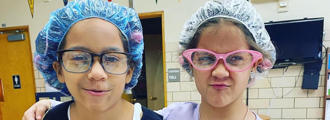 Two students wearing shower caps